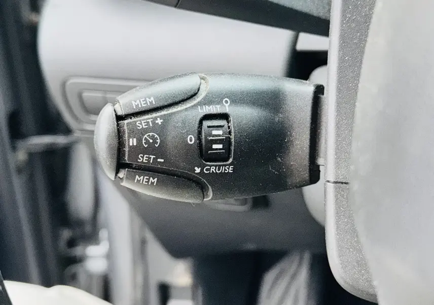 Gros plan sur la commande de régulateur de vitesse à gauche du volant dans l'habitacle du Citroën C3 Aircross gris 2020.