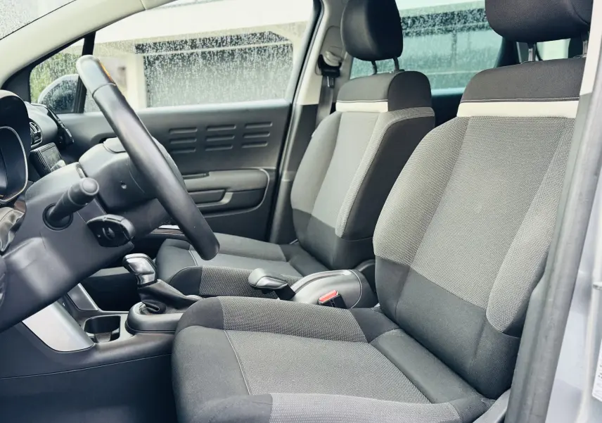Vue intérieure côté gauche montrant les sièges avant en tissu gris Mica et le volant en croûte de cuir du Citroën C3 Aircross 2020.