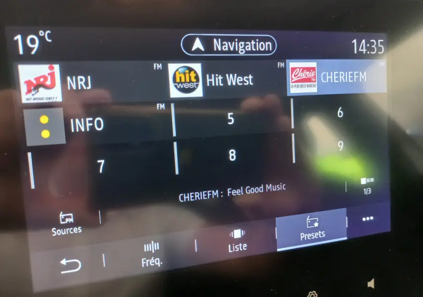 Écran tactile central de la Renault Clio Business blanc, affichant les stations radio FM et la navigation à 14h35.