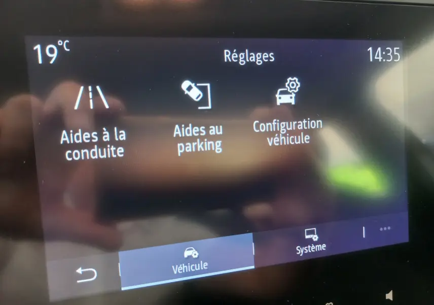 Écran tactile central de la Renault Clio Business blanc affichant les réglages d’aides à la conduite et au parking