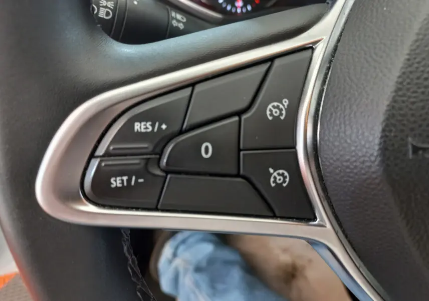 Gros plan sur les commandes de régulateur de vitesse au volant cuir noir de la Renault Clio Business blanche de 2021.