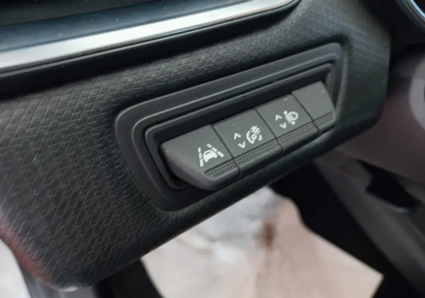 Gros plan sur les boutons de contrôle d'assistance à la conduite dans l'habitacle d'une Renault Clio Business blanche.