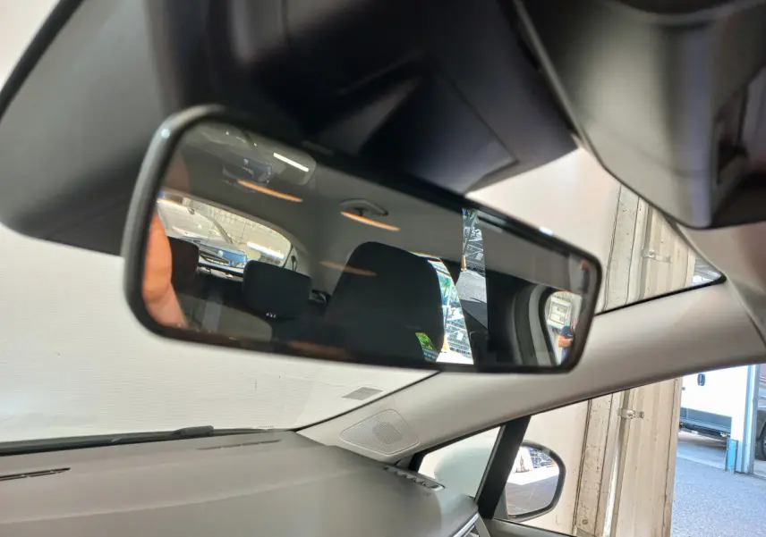 Vue intérieure du rétroviseur central d'une Renault Clio Business blanche, montrant l'arrière du véhicule et ses sièges noirs.