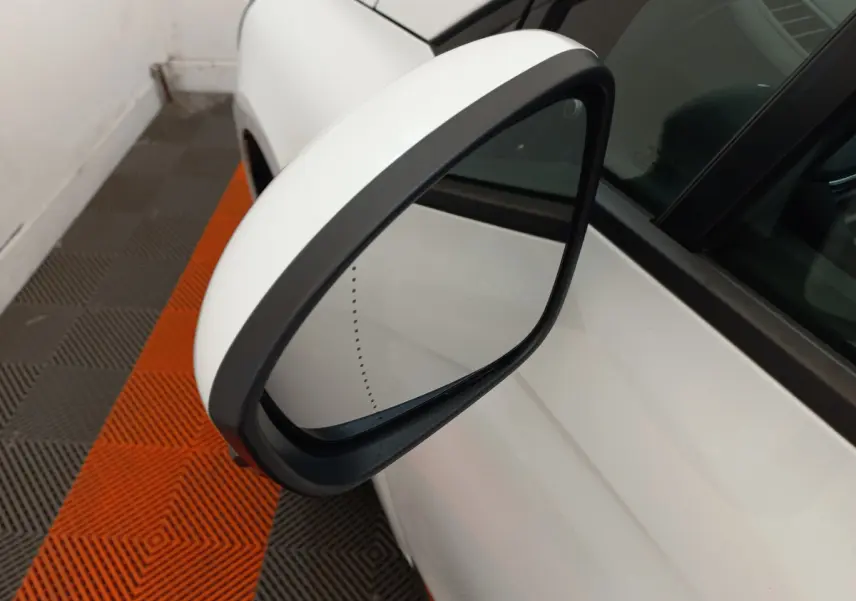 Rétroviseur extérieur droit blanc de Renault Clio Business 2021, vue rapprochée sur fond de sol orange et gris.