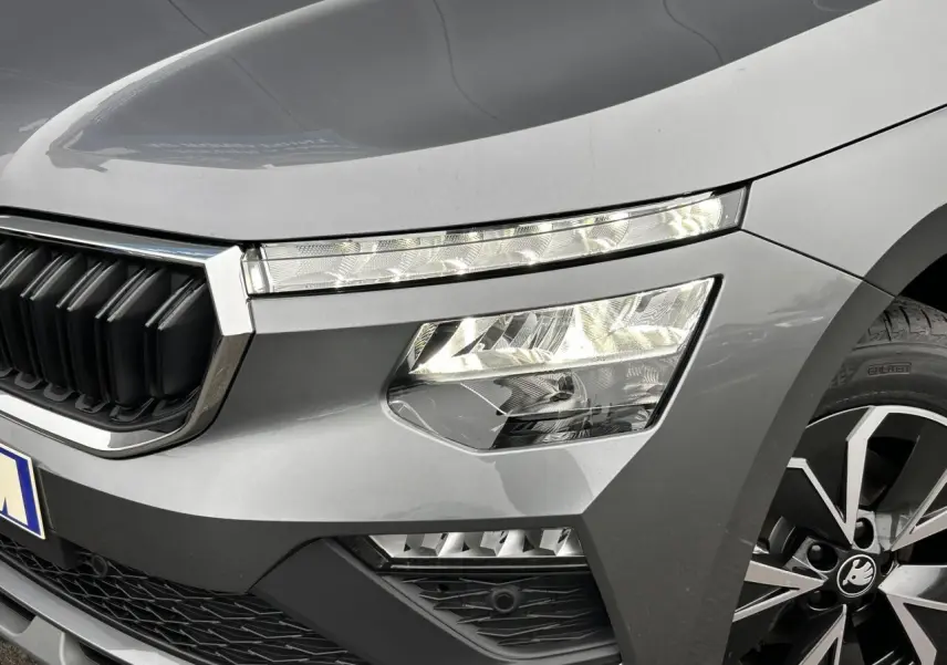 Gros plan sur l'avant droit du Skoda Kamiq gris graphite, mettant en valeur les phares Full LED et la calandre chromée.