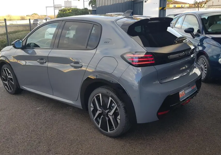 Vue 3/4 arrière droite d’une Peugeot 208 Hybrid 110 GT gris avec jantes alliage 17 pouces et toit noir brillant.