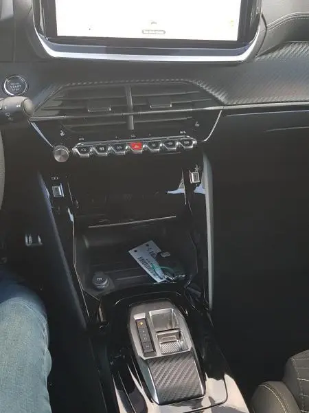 Vue intérieure centrée sur la console centrale de la Peugeot 208 Hybrid 110 e-DCS6 GT 2025, avec écran tactile et levier de boîte auto.