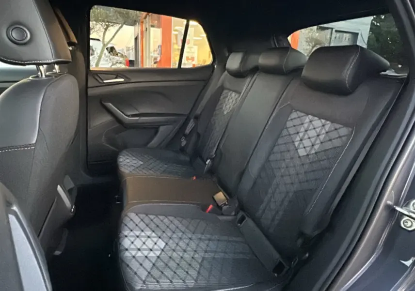 Vue intérieure arrière côté droit du Volkswagen T-Cross gris cendré, montrant la banquette arrière en tissu avec motifs géométriques.