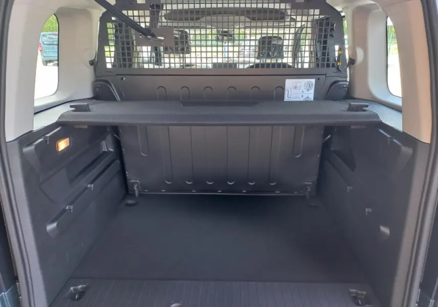 Vue arrière du coffre spacieux de l'Opel Combo Life M 2025 bleu avec séparation grillagée et tablette de rangement.