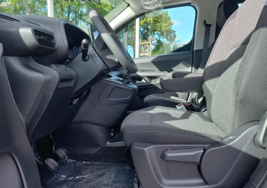 Vue intérieure côté conducteur de l'Opel Combo Life 2025, sièges gris et volant noir avec boîte manuelle.