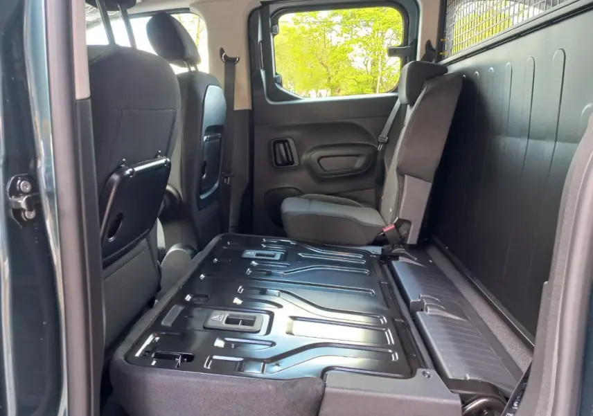 Vue intérieure côté droit de l’Opel Combo Life M 2025 bleu, montrant la banquette arrière rabattue et les sièges avant noirs.