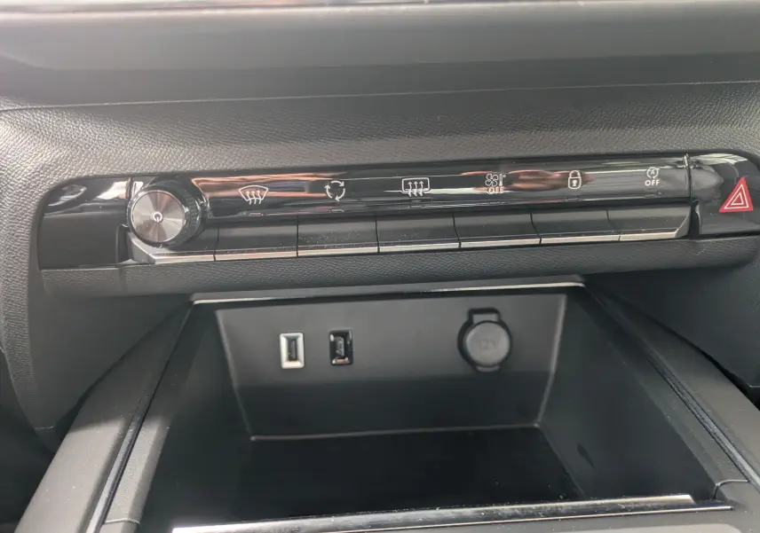 Vue rapprochée de la console centrale noire du Citroën C5 Aircross hybride 2025 avec commandes climatisation et ports USB.