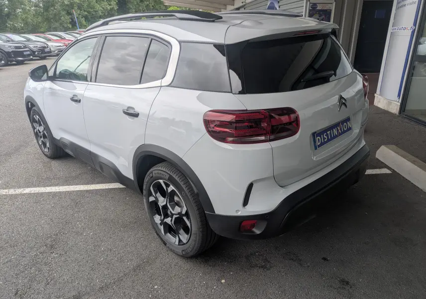 Vue 3/4 arrière droite d'un Citroën C5 Aircross hybride blanc Okenite avec jantes alliage biton et vitres arrière surteintées.