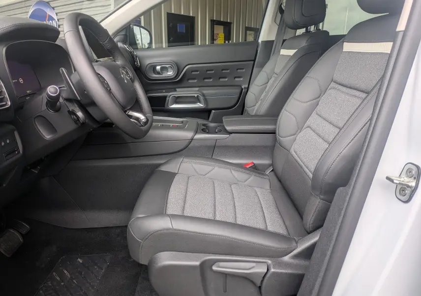 Vue intérieure côté conducteur du Citroën C5 Aircross hybride blanc Okenite, avec sièges tissu/TEP gris et volant cuir.