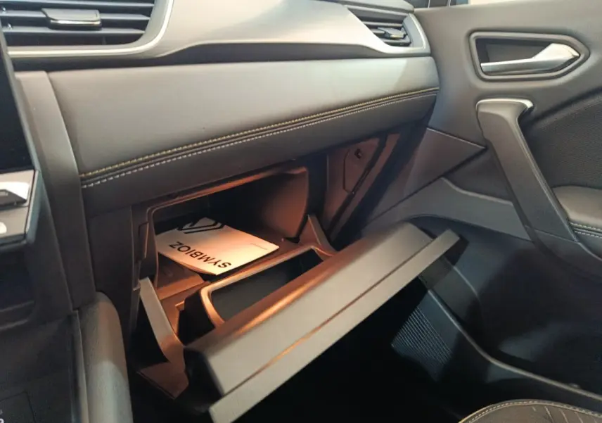 Intérieur côté passager du Renault SYMBIOZ noir, boîte à gants ouverte avec manuel visible.