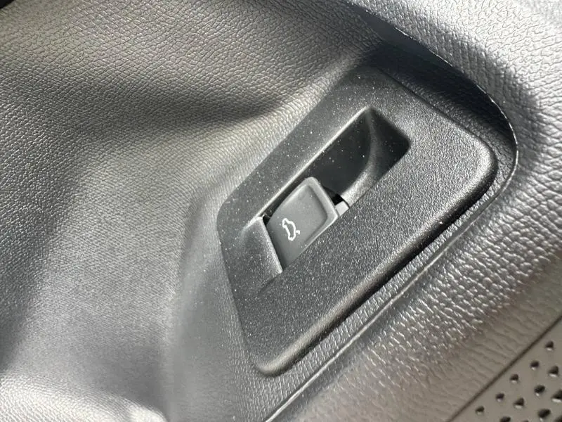 Gros plan sur le bouton d'ouverture du coffre noir intégré dans l'habillage intérieur noir du CUPRA Formentor 2.0 TDI.
