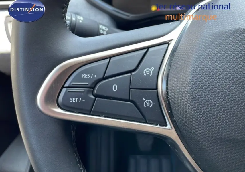 Gros plan sur les commandes de régulateur de vitesse au volant d’une Renault Clio rouge flamme métal, version 2025.