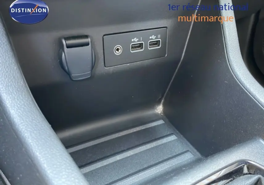 Gros plan sur la console centrale noire de la Renault Clio, montrant deux ports USB et une prise auxiliaire.