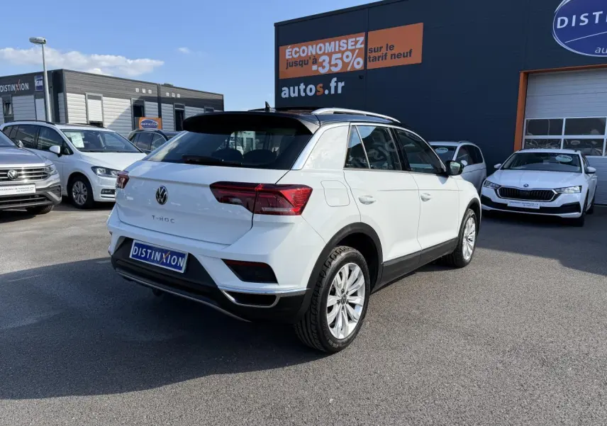 Volkswagen T-Roc blanc vue 3/4 arrière droit avec toit noir et jantes alliage sur parking extérieur.