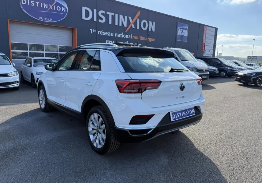 Volkswagen T-Roc blanc vue 3/4 arrière droit, avec toit noir et feux arrière LED distinctifs.