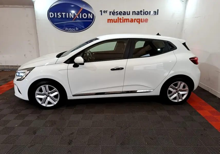 Profil droit d'une Renault Clio Business blanche 2021, avec jantes alliage et feux arrière LED visibles en intérieur showroom.