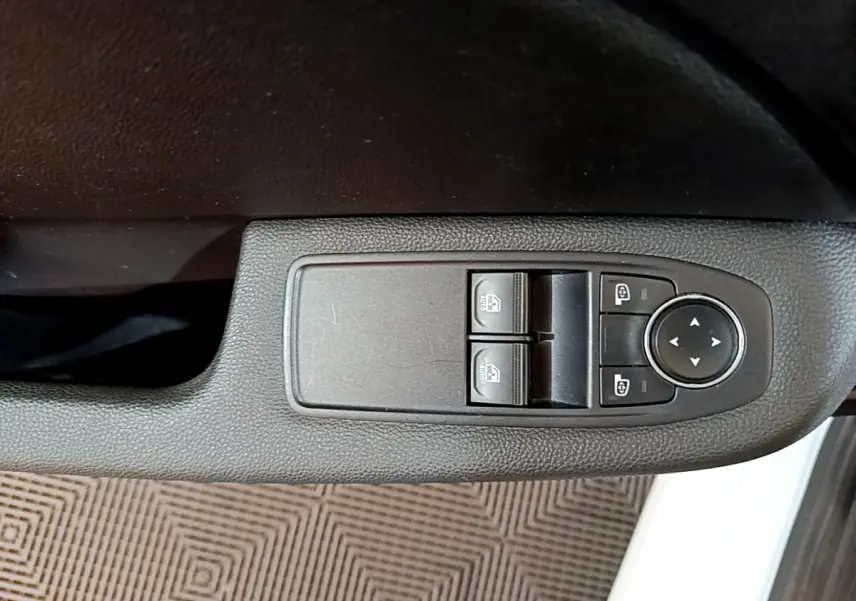 Gros plan sur les commandes de lève-vitres et rétroviseurs côté conducteur d'une Renault Clio Business blanche 2021.
