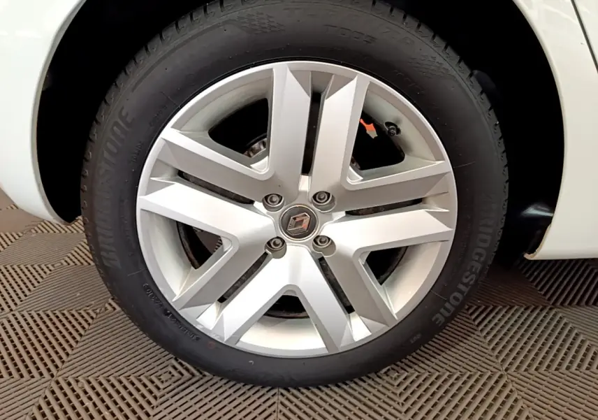 Gros plan sur la roue avant gauche blanche d'une Renault Clio Business 2021 avec jante alliage et logo Renault central.