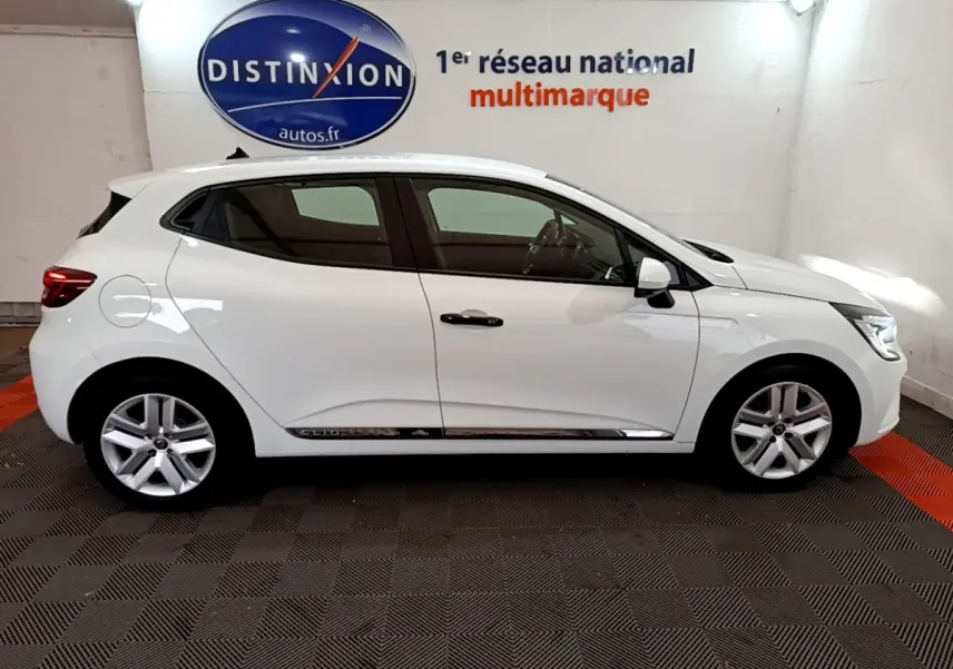 Profil droit d'une Renault Clio Business blanche 2021 avec jantes alliage et poignées noires dans un showroom.