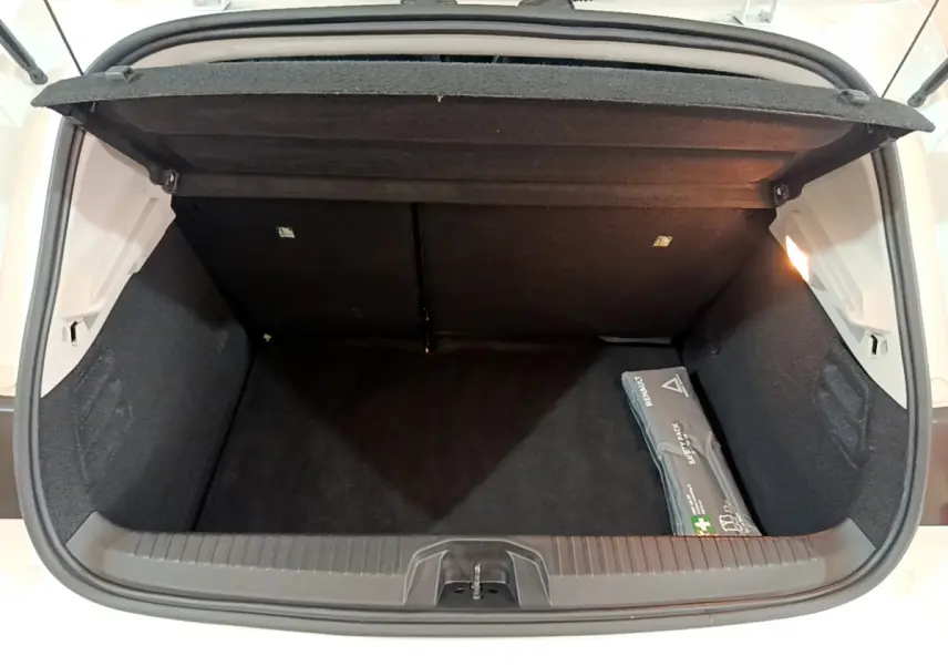 Coffre ouvert vu de l'arrière d'une Renault Clio Business blanche avec trousse de secours visible à droite.