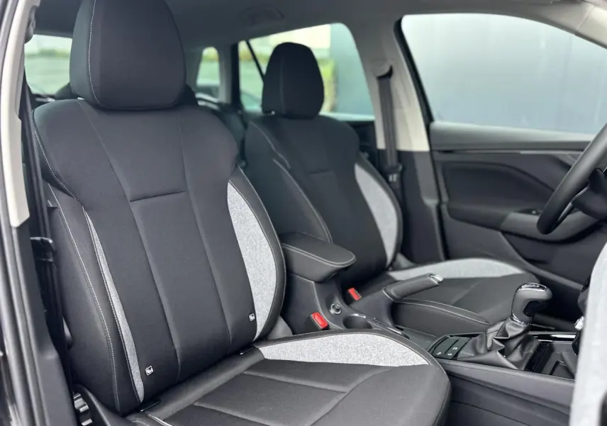 Vue intérieure côté conducteur du Skoda Kamiq 2025 noir Magic, sièges bi-matière noirs et gris avec surpiqûres blanches.