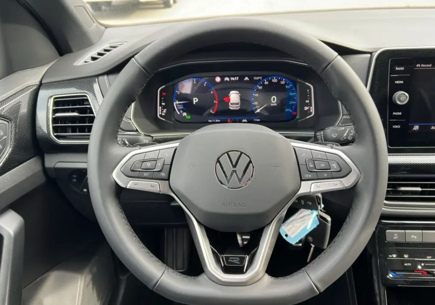 Vue centrée du volant cuir multifonctions avec logo Volkswagen et tableau de bord digital du T-Cross TSI 116 DSG7 R-Line 2025.