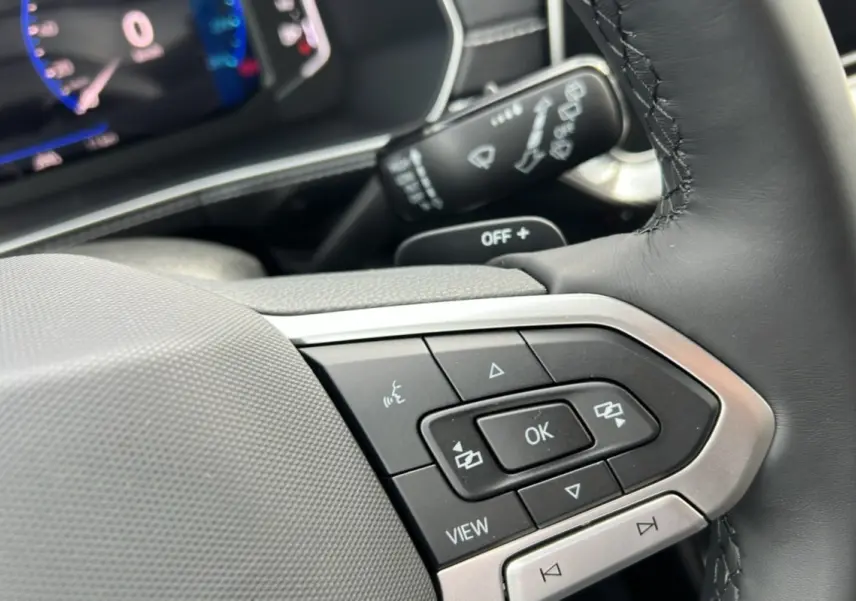 Gros plan sur le volant cuir multifonctions côté gauche du Volkswagen T-Cross gris argent avec commandes intégrées.