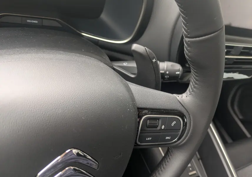Gros plan sur le volant en cuir noir du Citroën C5 Aircross hybride 2025, avec commandes intégrées côté droit.