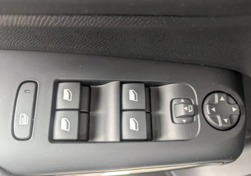 Gros plan sur les commandes de lève-vitres et réglages des rétroviseurs côté conducteur du Citroën C5 Aircross gris platinium.