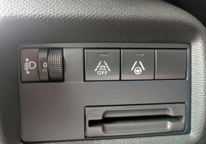 Gros plan sur les commandes de réglage des phares et d’aide à la conduite du tableau de bord du Citroën C5 Aircross gris platinium.