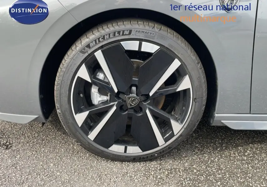 Gros plan sur la roue avant gauche de la Peugeot 308 gris selenium métal, mettant en valeur la jante noire et argentée au design moderne.