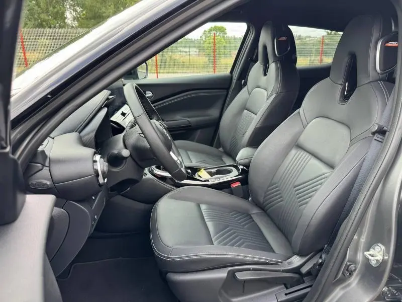 Vue intérieure côté conducteur du Nissan Juke 2025 noir Kuro, avec sièges sport en tissu et volant cuir multifonction.