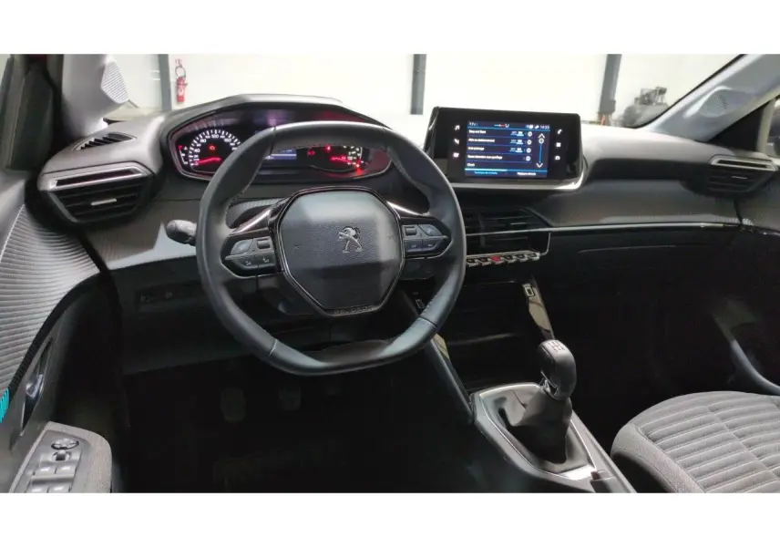Vue intérieure avant du poste de conduite de la Peugeot 208 2024, avec volant compact et écran tactile central.