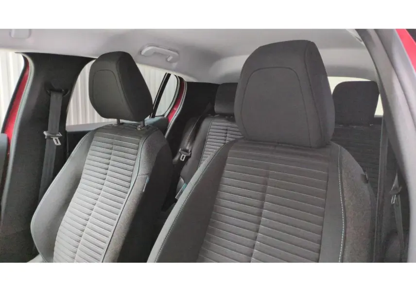Vue intérieure des sièges avant et arrière noirs de la Peugeot 208 2024 Rouge Elixir, côté conducteur ouvert.