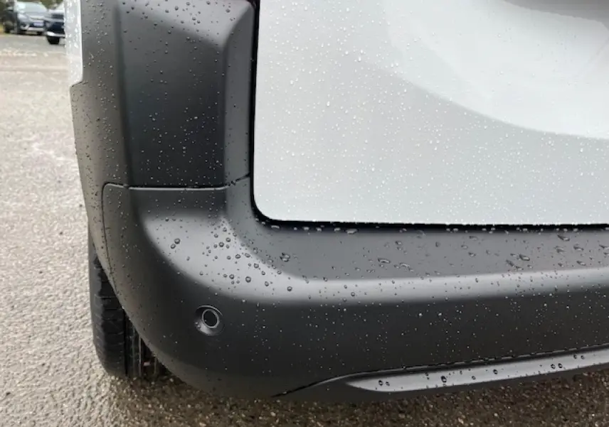 Gros plan sur l'angle arrière gauche du Citroën Berlingo Multispace blanc 2025, avec pare-chocs noir et capteur de recul.