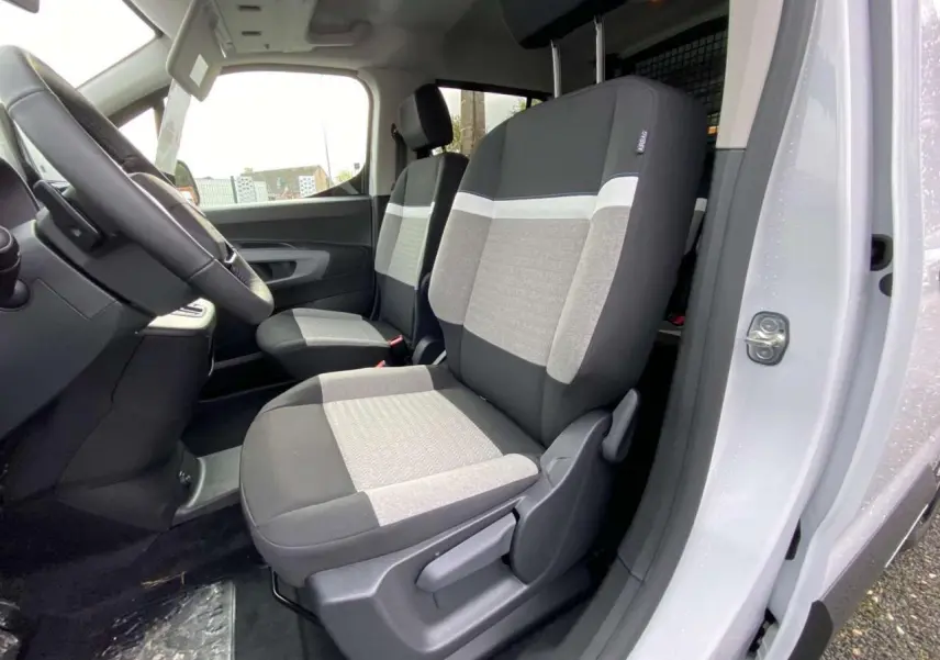 Vue intérieure côté conducteur du Citroën Berlingo Multispace blanc 2025, montrant les sièges avant bi-ton gris et noir.