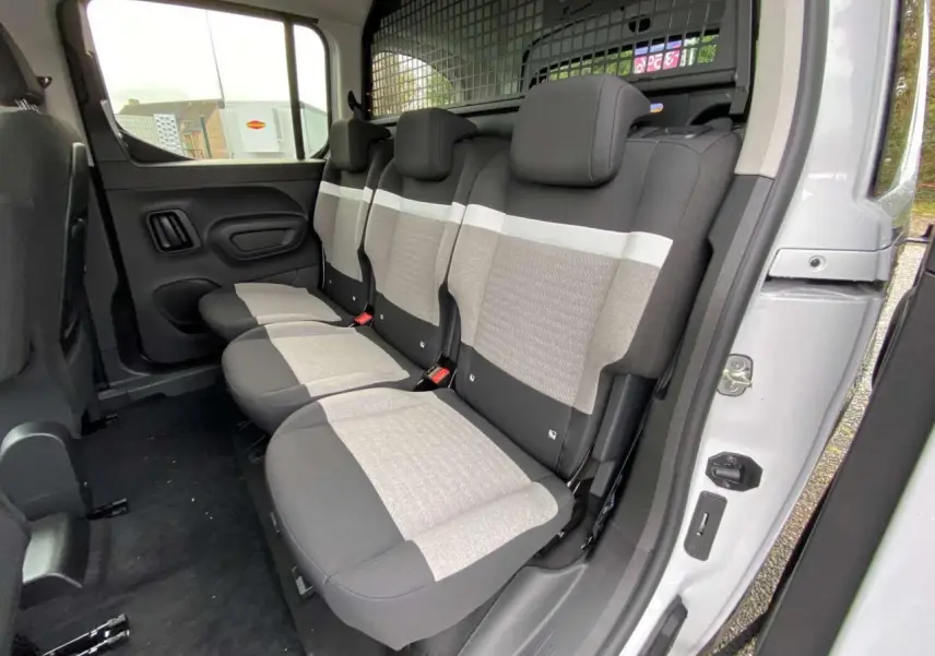 Vue intérieure côté droit des sièges arrière gris et noirs du Citroën Berlingo Multispace blanc 2025 avec séparation grillagée.