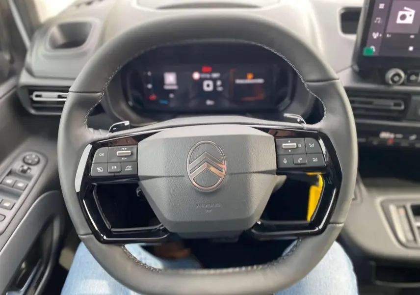 Vue rapprochée du volant noir du Citroën Berlingo Multispace 2025, avec commandes intégrées et tableau de bord numérique.