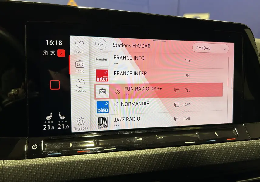Écran tactile central de la Volkswagen Golf VIII eTSI 150CH R-Line affichant les stations FM/DAB avec réglage de la température à 21,5°C.