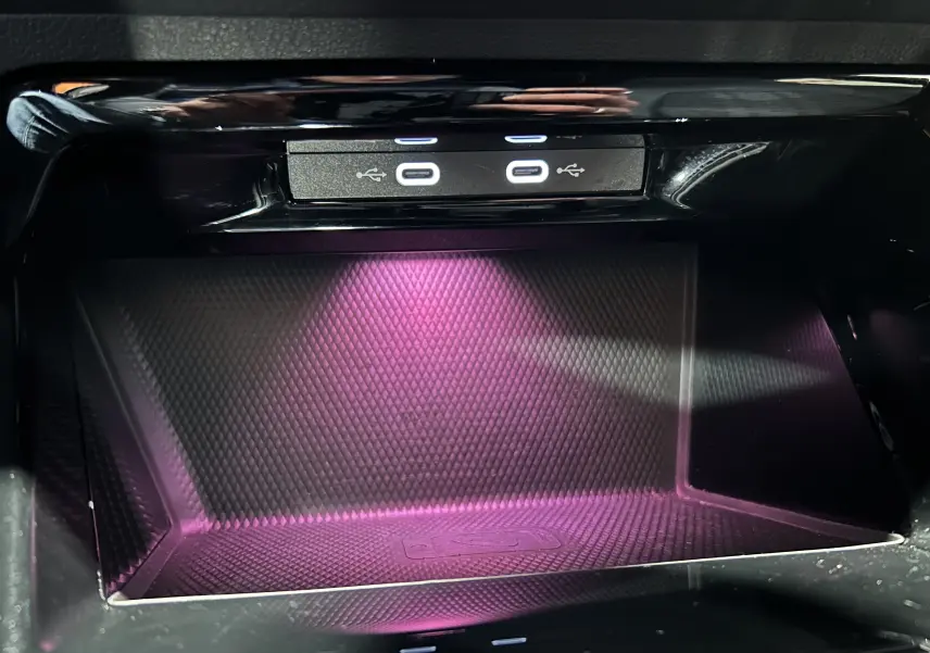 Gros plan sur la zone de recharge USB avec éclairage violet à l'intérieur d'une Volkswagen Golf VIII eTSI noire.