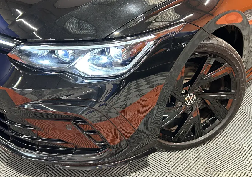 Gros plan sur l'avant droit noir métal d'une Volkswagen Golf VIII eTSI 150CH avec phare LED et jante noire R-Line.