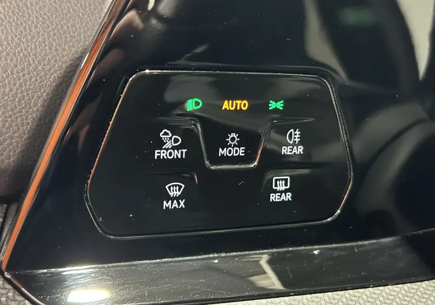 Gros plan sur les commandes d’éclairage et dégivrage du tableau de bord noir brillant de la Volkswagen Golf VIII eTSI 2024.