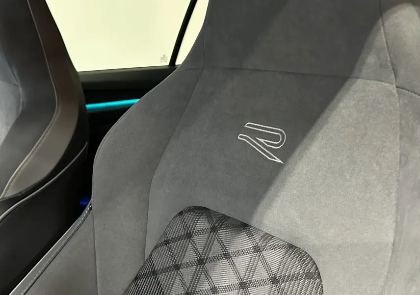 Gros plan sur le siège avant en tissu gris foncé avec logo R brodé, intérieur d’une Volkswagen Golf VIII eTSI noir métal.