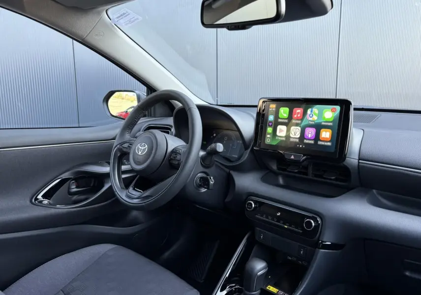 Intérieur avant de la Toyota Yaris hybride 2025, vue côté conducteur montrant le volant cuir et l’écran tactile central.