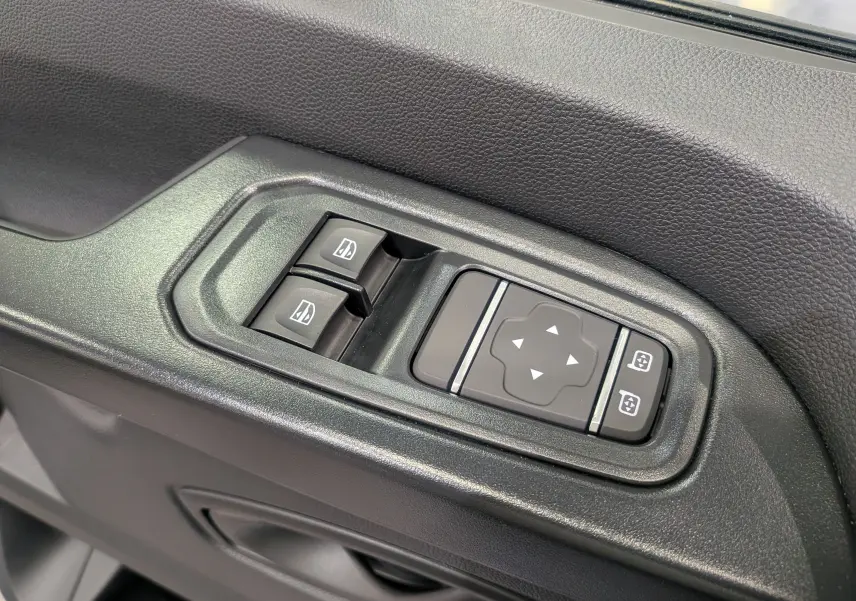 Gros plan sur les commandes de lève-vitres et réglage des rétroviseurs côté conducteur du Renault Trafic Combi gris.